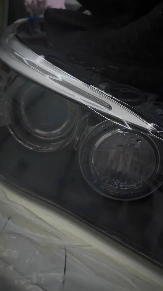 Close-up of a vehicle headlight during a clarity-restoration treatment.